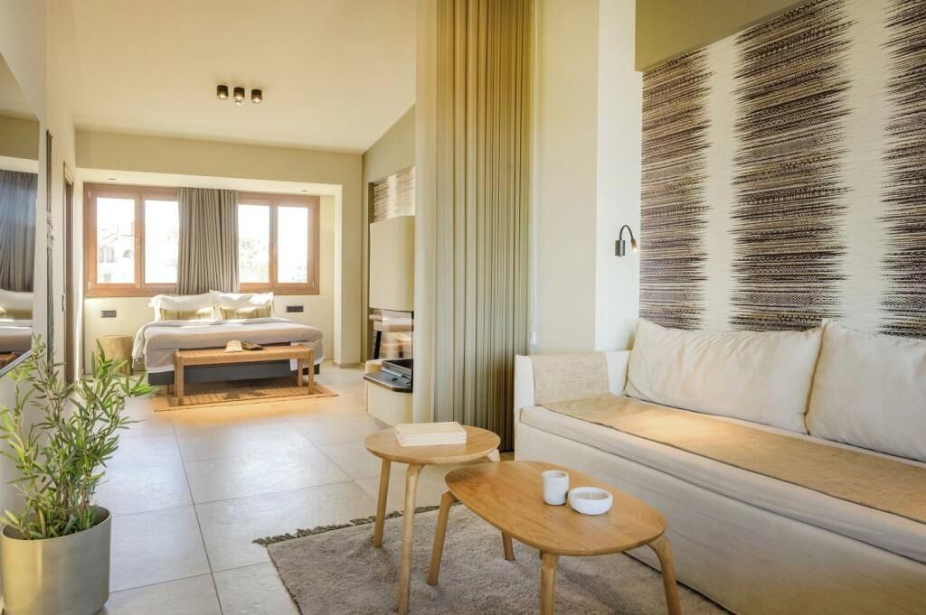 Una camera d'albergo moderna con un letto, un divano, un tavolino e una pianta in vaso.