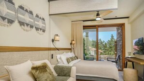 Un dormitorio con cama, sofá, ventilador de techo y vistas al exterior.