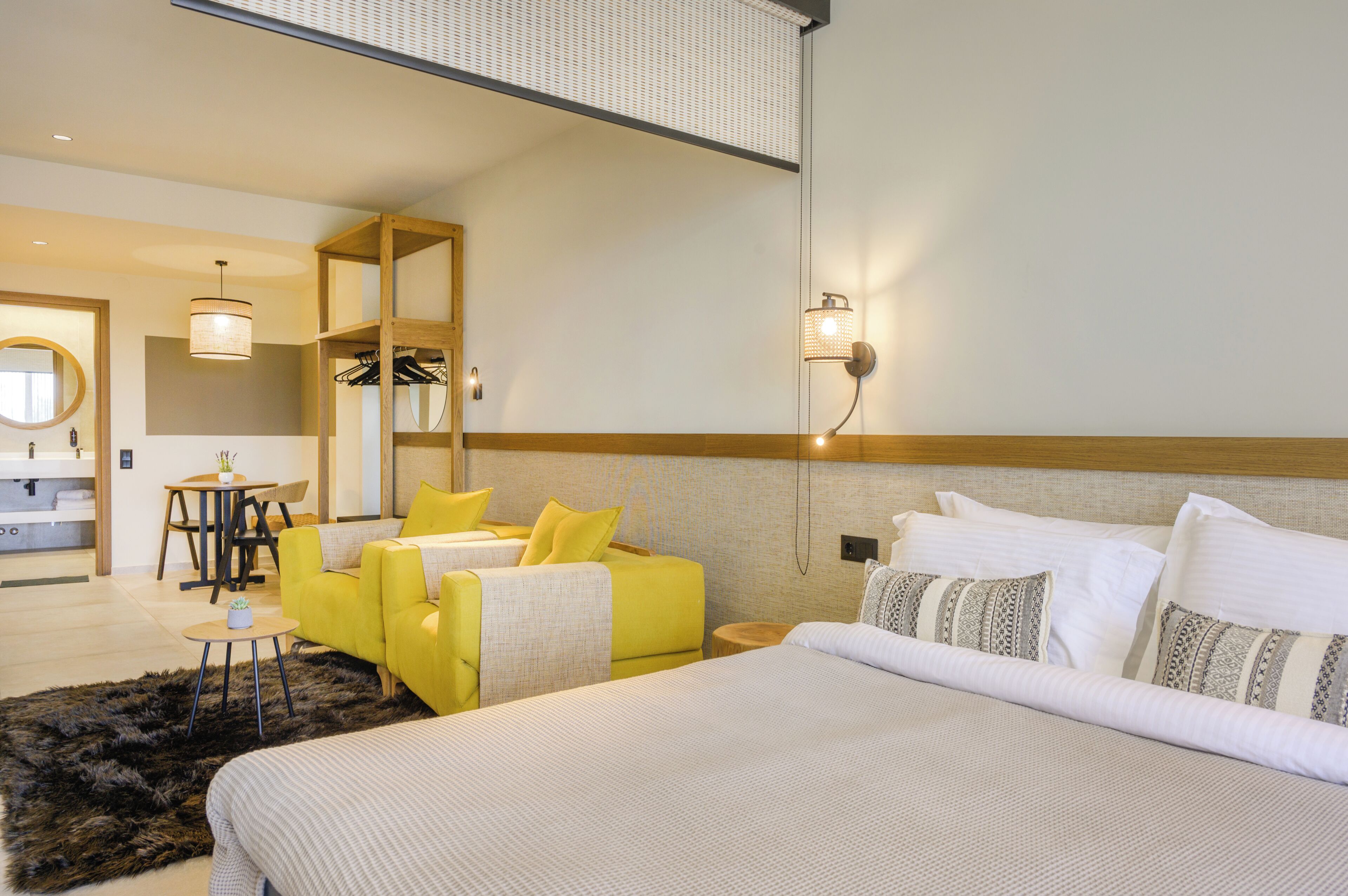 Ein Hotelzimmer mit einem Bett, einem gelben Sofa, einem kleinen Tisch und einem Spiegel.