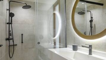 Un bagno moderno con doccia vetrata, uno specchio grande e un mobile lavabo bianco.