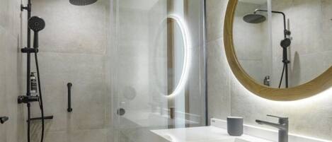 A modern bathroom with a glass-enclosed shower, a large mirror, and a white vanity.