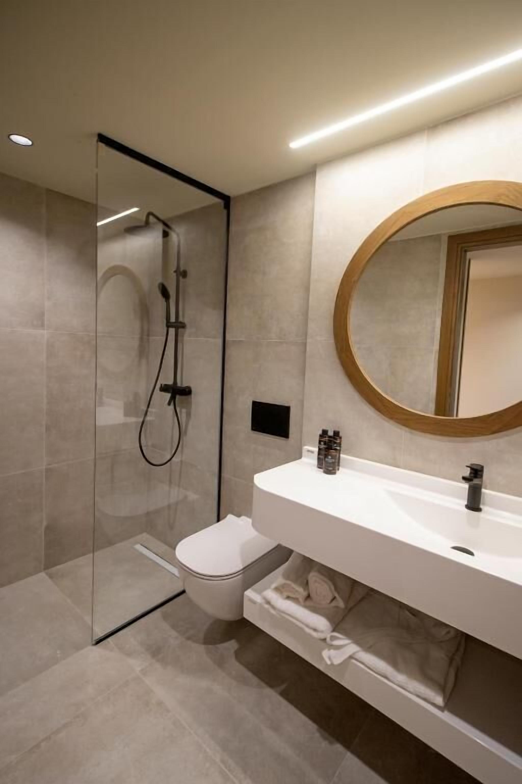 A modern bathroom with a glass-enclosed shower, a white sink, and a large mirror.