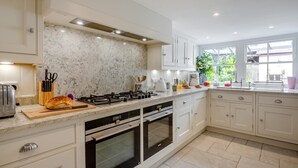 Een moderne keuken met een gasfornuis, oven en een marmeren spatwand.