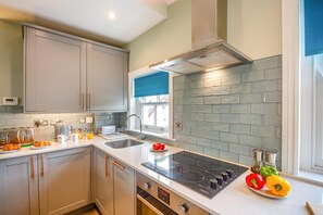 A modern kitchen with grey cabinets, a stainless steel range, and a window with a view. - 3 Bed in Beaumaris (oc-h44704) (Beaumaris)