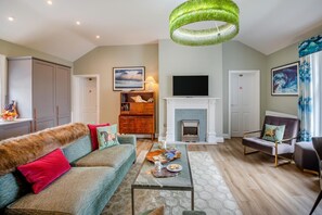 A living room with a sofa, coffee table, fireplace, television, and a decorative ceiling light. - 3 Bed in Beaumaris (oc-h44704) (Beaumaris)