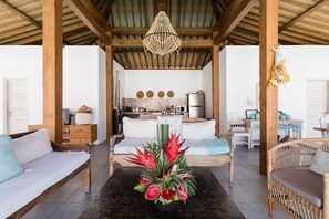 A cozy room with a bed, a sofa, a dining area, and a kitchen in the background. - Exquisite Architectural Villa with Outdoor Pool (Seminyak)