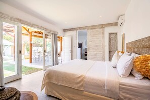 A bedroom with a large bed, a view of the outdoor patio, and a modern design. - Exquisite Architectural Villa with Outdoor Pool (Seminyak)