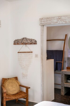 A room with a wooden chair, a wall hanging, and a mirror. - Exquisite Architectural Villa with Outdoor Pool (Seminyak)