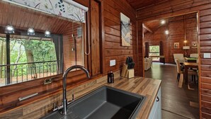 A wooden cabin interior with a kitchen area, a dining space, and a view of the outdoors. - 3 Bed in Llanrwst (oc-a43648) (Llanrwst)