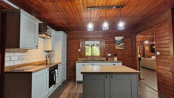 Une cuisine moderne avec des murs en bois, un îlot central et des luminaires suspendus.