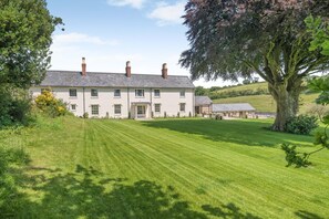 A large, single-story building with a symmetrical facade, multiple chimneys, and a well-maintained lawn in front. - 6 Bed in Chebbard (oc-c43267) (Puddletown)