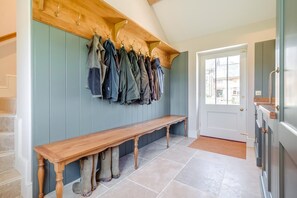 A hallway with a bench, a coat rack with multiple jackets, and a door leading outside. - 6 Bed in Chebbard (oc-c43267) (Puddletown)