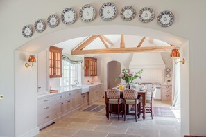 A kitchen with an arched doorway, wooden beams, white cabinetry, and a dining area with a table set for four. - 6 Bed in Chebbard (oc-c43267) (Puddletown)