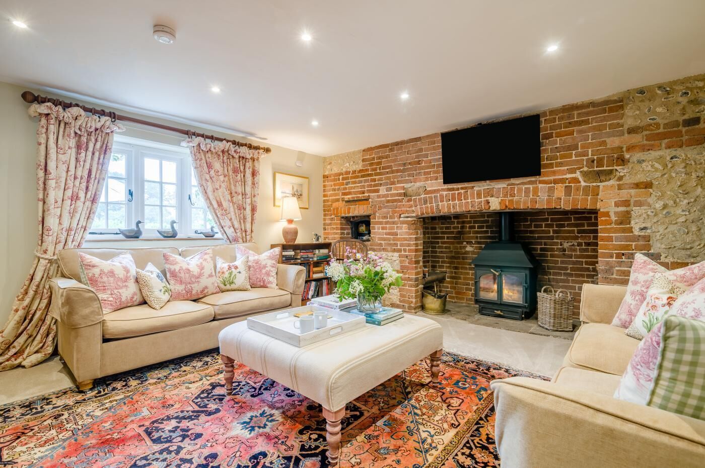 A cozy living room with a brick fireplace, a sofa, a coffee table, and a patterned rug.