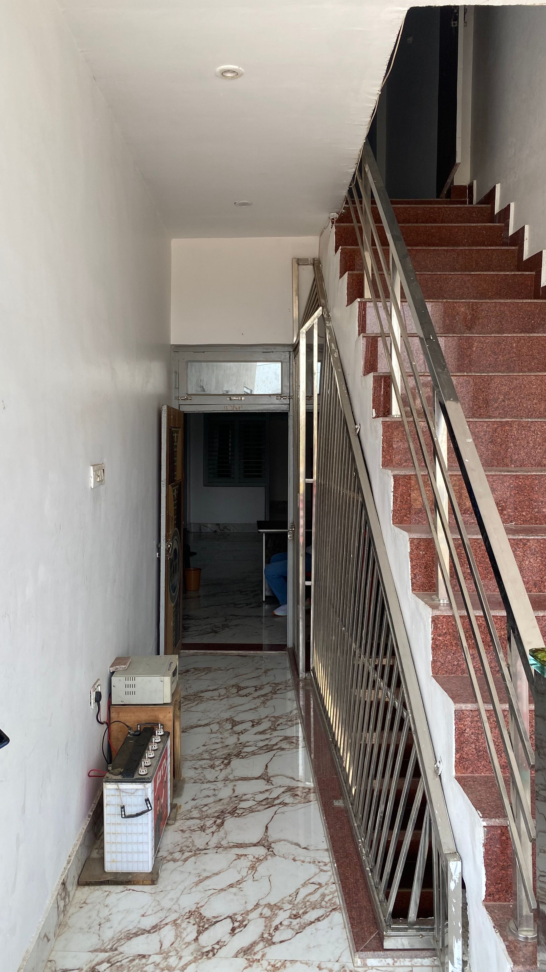 Ein Flur mit Treppe, Marmorboden und einer Tür zu einem weiteren Raum.