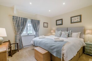 A bedroom with a large bed, a window with curtains, a bedside table with a lamp, a chair, and a small cabinet. - 2 Bed in Chebbard (oc-p43269) (Puddletown)