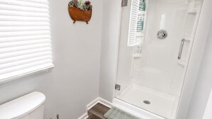 A bathroom with a toilet, a shower with a glass door, and a wooden floor. - Spacious 5BD 2BA Home Close To Oakbrook (Westmont)