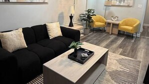 A modern living room with a black sofa, wooden coffee table, and yellow armchairs. - Spacious 5BD 2BA Home Close To Oakbrook (Westmont)