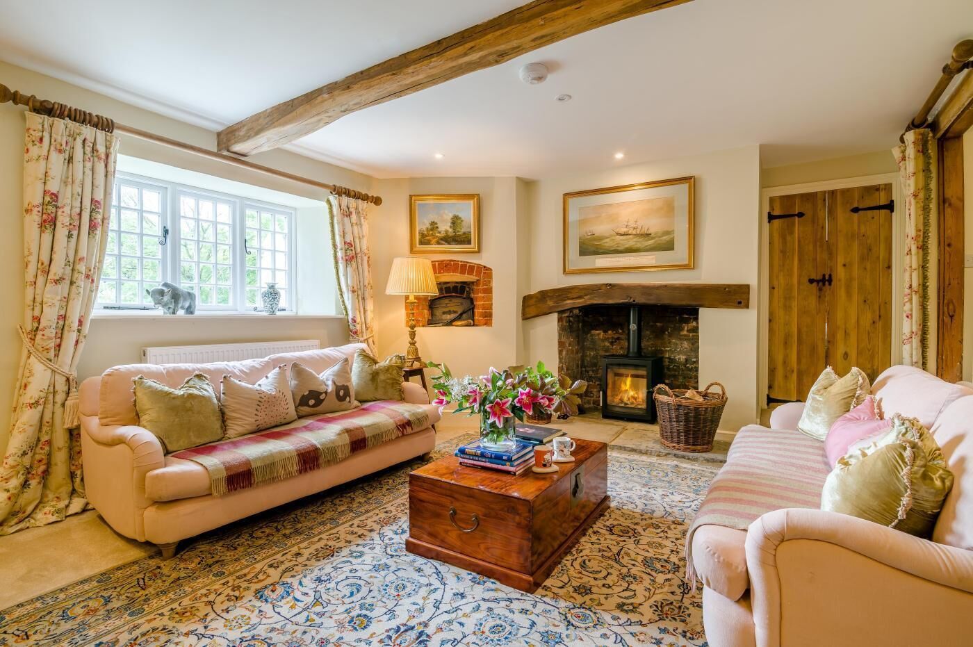 A cozy living room with a fireplace, two sofas, a coffee table, and a large window with curtains.