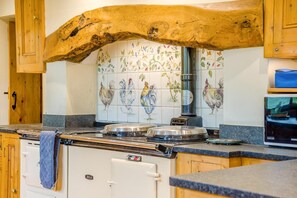 A kitchen with a rustic wooden beam, a tiled backsplash with roosters, a stove, and a Samsung refrigerator. - 4 Bed in Chebbard (oc-c43270) (Puddletown)