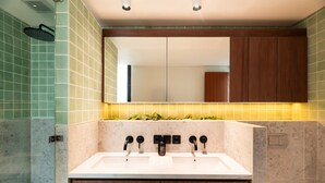Un baño moderno con lavamanos doble, armarios de madera y un espejo sobre el lavamanos.