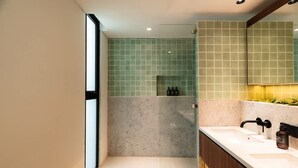 Un baño moderno con un espejo grande, un lavamanos blanco y una zona de ducha.