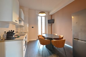 Eine moderne Küche mit Essbereich, Backofen, Kaffeemaschine und einem wandmontierten Flachbildfernseher.