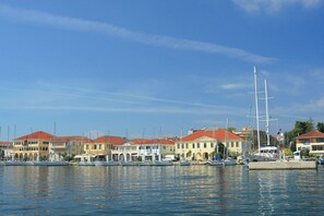 A marina with multiple boats docked, a large sailboat, and buildings with red roofs.