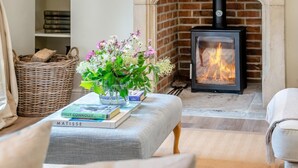 A cozy living room with a fireplace, a bookshelf, and a vase of flowers. - 1 Bed in Chebbard (oc-d43272) (Puddletown)