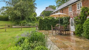 A brick house with a patio area, a table with chairs, and a garden. - 1 Bed in Chebbard (oc-d43272) (Puddletown)