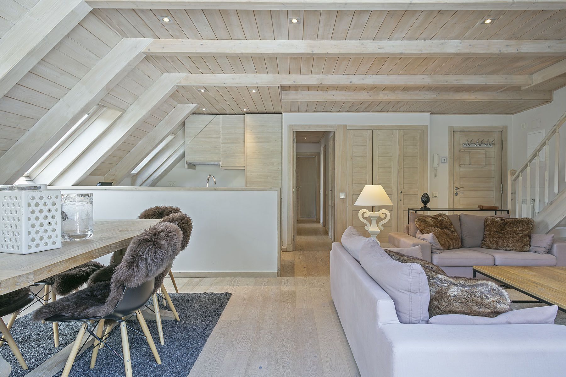 Un espace de vie de style loft avec un plafond haut, un coin repas comprenant une chaise et une table, un canapé avec des coussins et une lampe.