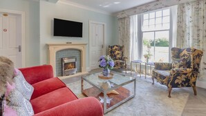 Un salon avec une cheminée, un téléviseur et deux fauteuils.