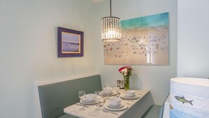 Un coin repas avec une table dressée pour quatre personnes, un banc, un tableau encadré, un luminaire décoratif et un mur orné d’un tableau.