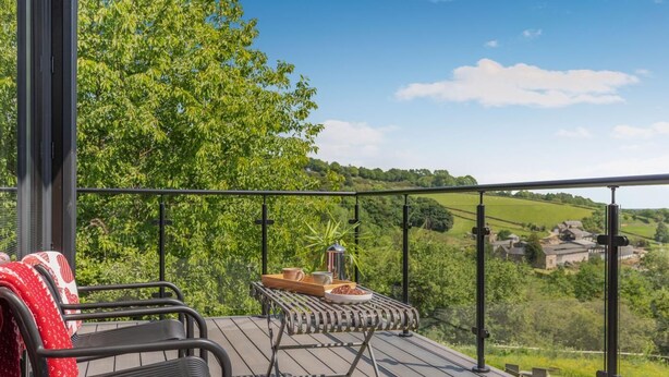 Ein Balkon mit Blick auf eine grüne Landschaft, ein Tisch mit Tablett und zwei Stühle.