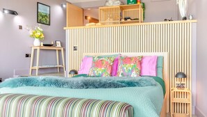 Ein Schlafzimmer mit Etagenbett, Nachttisch, Lampe, Erste-Hilfe-Kasten und einer Wandablage.