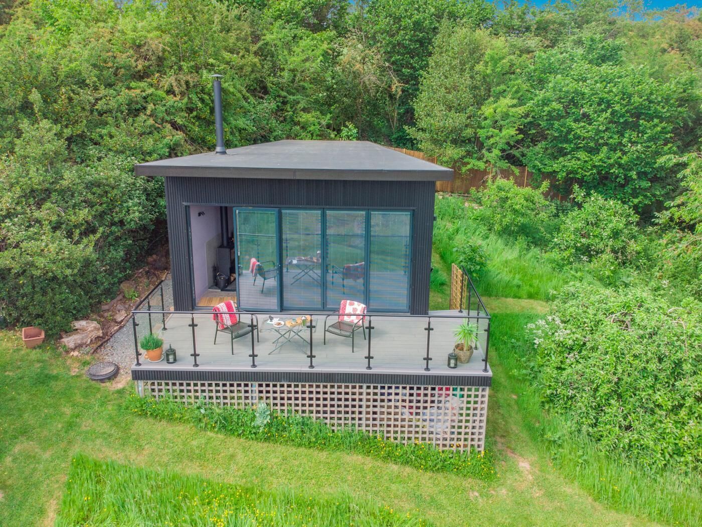 Una casa moderna con balcón, puerta corredera de vidrio y jardín.