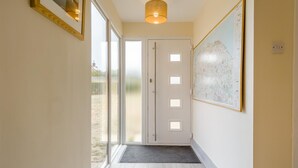 En gang med en dør der fører til en balkon, et kort på væggen og en lampe over sig.