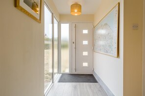 A hallway with a door leading to a balcony, a map on the wall, and a light fixture above. - 3 Bed in Mundesley (oc-s44224) (Mundesley)