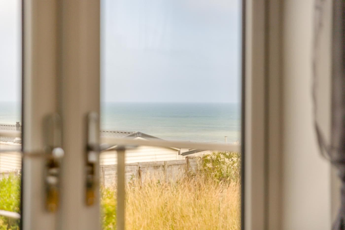 A view through a door to a beach with a clear sky.