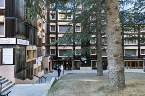 Un immeuble à plusieurs étages doté d’une cour intérieure, d’un espace extérieur aménagé pour s’asseoir et d’un escalier menant à l’entrée.