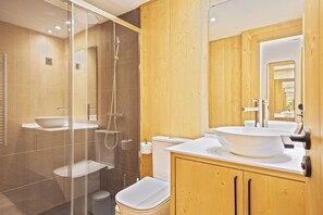 Une salle de bain moderne avec une douche à parois de verre, un grand lavabo et des meubles en bois.