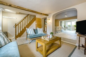 Ein Wohnzimmer mit einer Couch, einem Couchtisch, einem Fernseher und einer Treppe.
