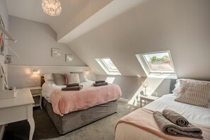 A bedroom with two beds, a desk, and a chair. There are skylights and a chandelier. - 4 Bed in Skirlaugh (oc-w43303) (Skirlaugh)