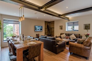 A modern living room with a dining area, leather sofas, a fireplace, and large windows. - 4 Bed in Skirlaugh (oc-w43303) (Skirlaugh)