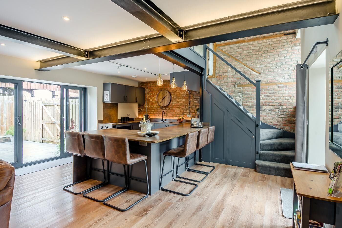 Une cuisine moderne avec un coin bar, un plancher en bois et un mur en briques.