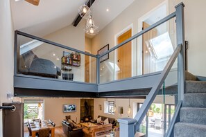 A spacious living area with a fireplace, a dining table set for four, and a staircase leading to an upper level. - 4 Bed in Skirlaugh (oc-w43303) (Skirlaugh)