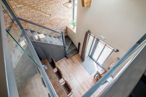 A staircase with glass railings leading to a lower level, a wooden floor, and a window with curtains. - 4 Bed in Skirlaugh (oc-w43303) (Skirlaugh)