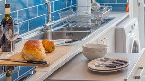 A kitchen with a bread loaf, apples, a wine bottle, and a sink. - 2 Bed in Weymouth (oc-s42788) (Weymouth)