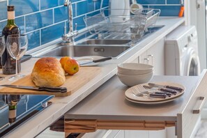 A kitchen with a bread loaf, apples, a wine bottle, and a sink. - 2 Bed in Weymouth (oc-s42788) (Weymouth)