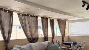 Ett rum med en soffa, ett litet bord, en stol och ett fönster med gardiner.